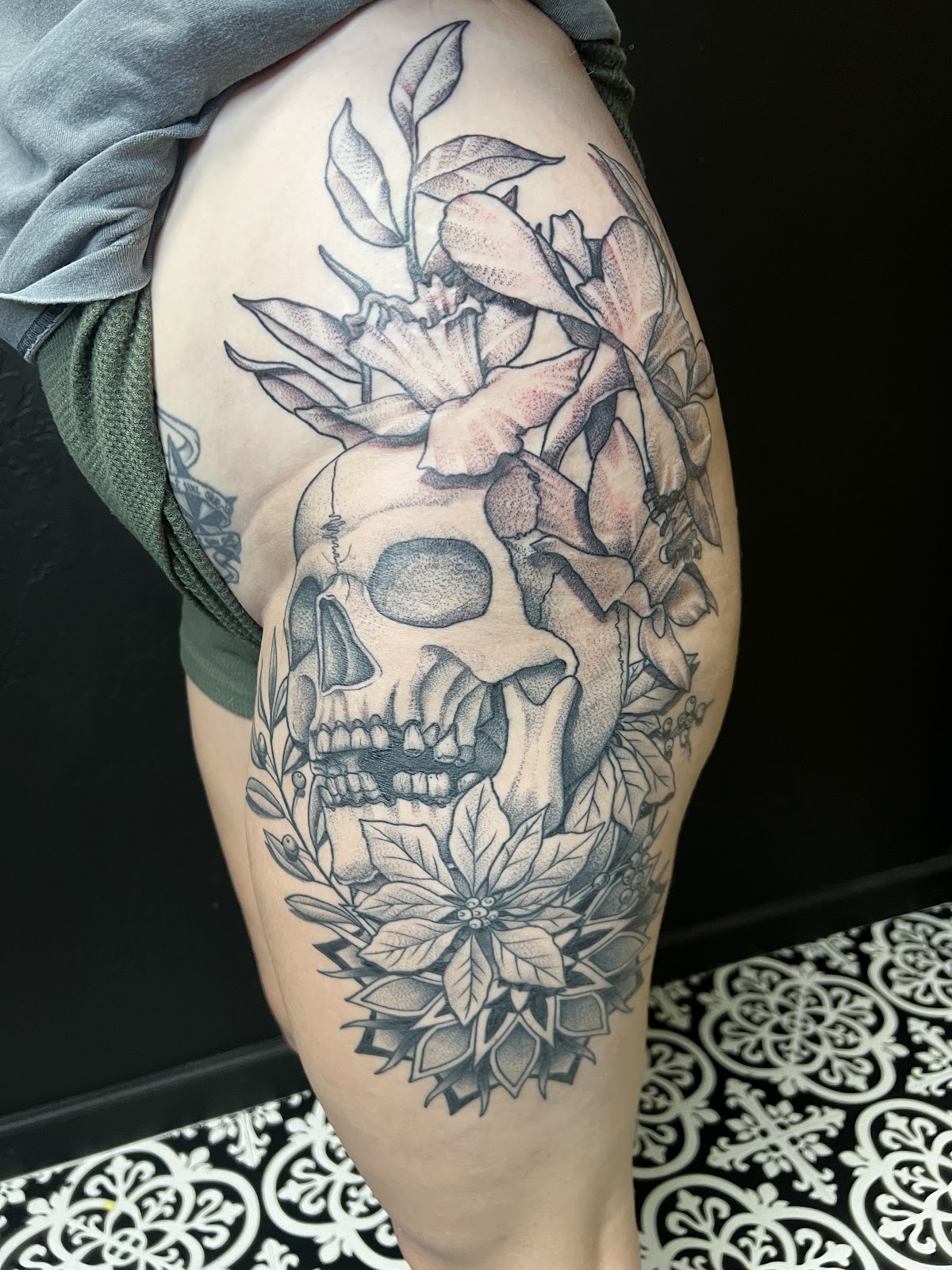 Black and gray skull with flowers and dotwork mandala on a thigh