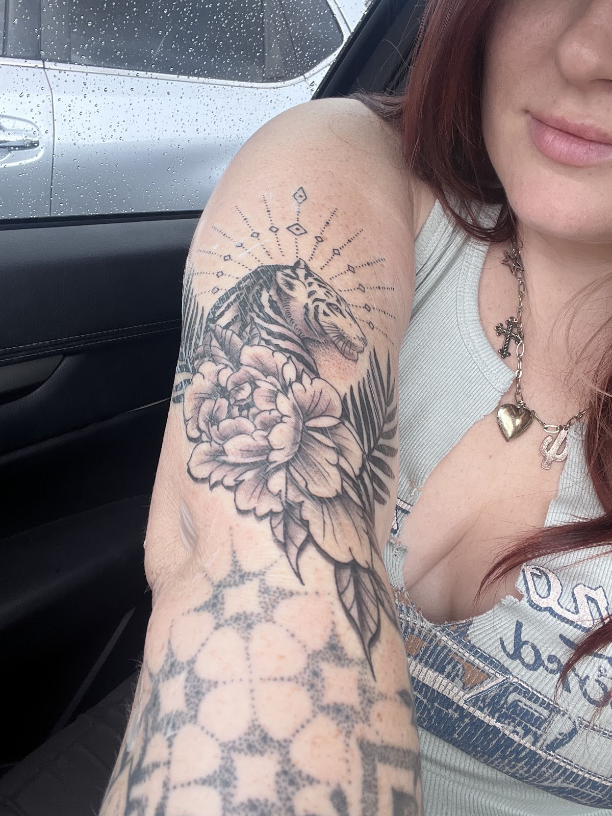 Black and gray tiger with peony and fern on an upper arm