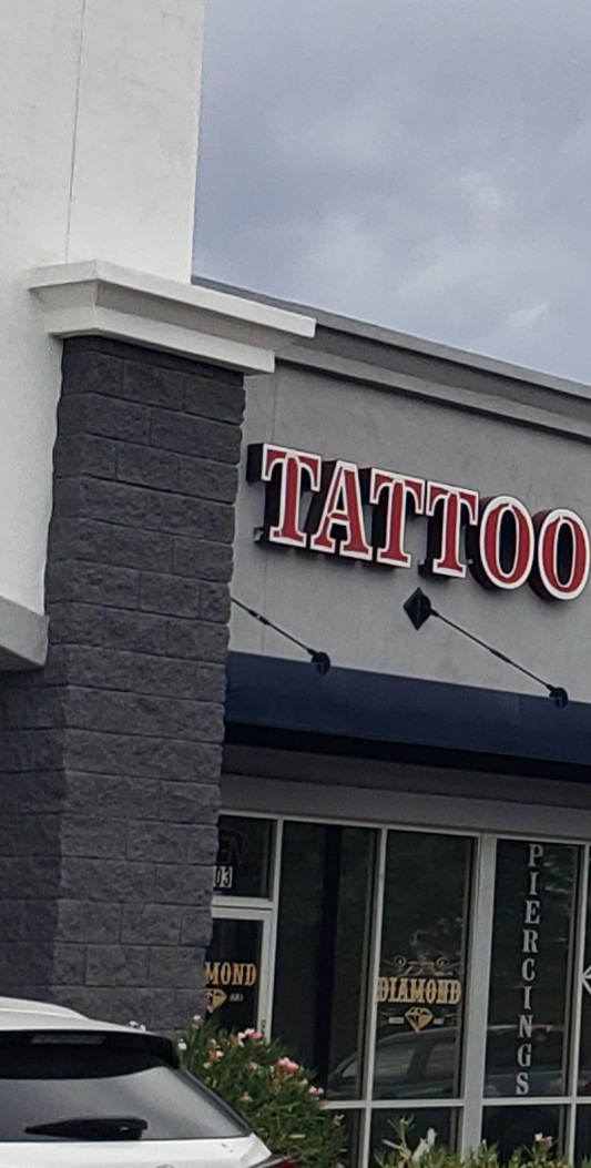 Our storefront on S Crismon Rd: red TATTOO channel letters with a black diamond, DIAMOND lettering and PIERCINGS vinyl on the glass