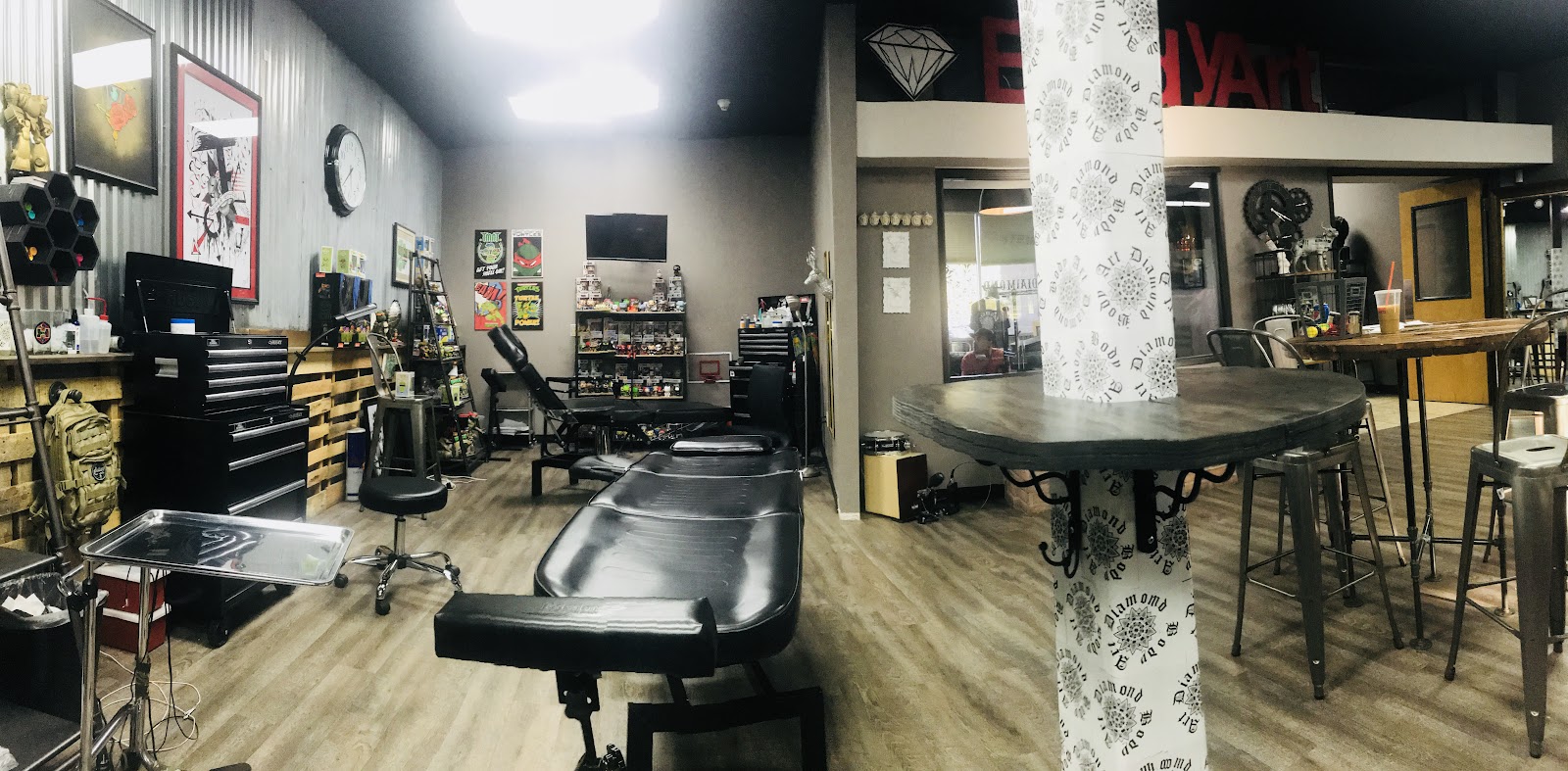 Inside Diamond Body Art: tattoo stations, black tool chests, corrugated steel wall, and the pillar wrapped in our diamond logo paper