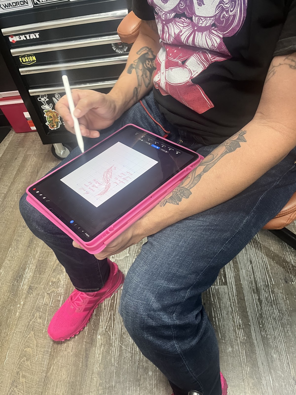 Custom script and feather design being drawn on a tablet at the shop, tool chest behind